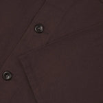Close-up of a Dark Plum  fabric with buttons and a pocket