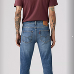 Person wearing blue jeans and a maroon t-shirt on a plain background