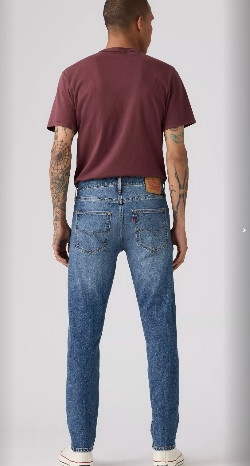 Person wearing blue jeans and a maroon t-shirt on a plain background