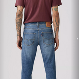 Person wearing blue jeans and a maroon t-shirt on a plain background