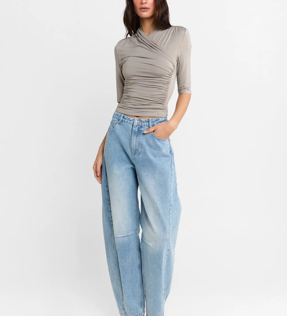 A woman shown wearing a Steel grey half-sleeve ribbed  top and light-wash wide-leg denim jeans, paired with white heels, against a plain white studio background.