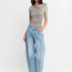 A woman shown wearing a Steel grey half-sleeve ribbed  top and light-wash wide-leg denim jeans, paired with white heels, against a plain white studio background.
