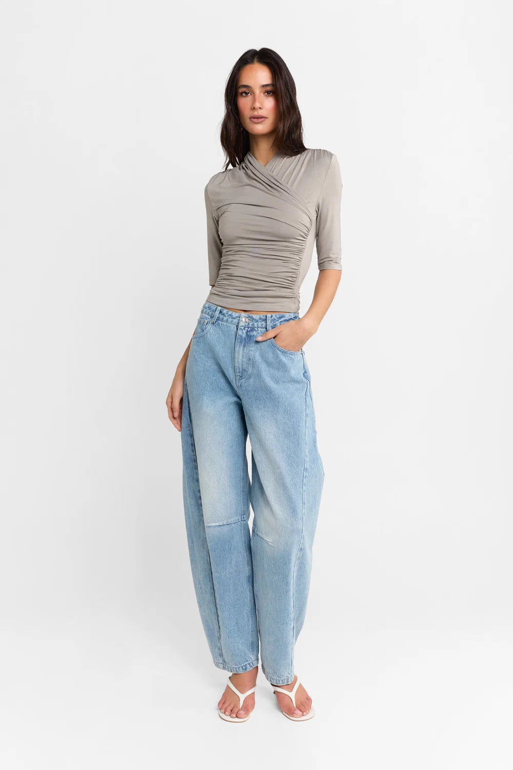 A woman shown wearing a Steel grey half-sleeve ribbed  top and light-wash wide-leg denim jeans, paired with white heels, against a plain white studio background.