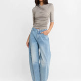 A woman shown wearing a Steel grey half-sleeve ribbed  top and light-wash wide-leg denim jeans, paired with white heels, against a plain white studio background.