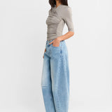 A woman shown from the side wearing a Steel grey half-sleeve ribbed  top and light-wash wide-leg denim jeans, paired with white heels, against a plain white studio background.