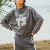 Person wearing a gray sweatshirt with a number 75 and pants outdoors.