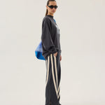 Person wearing a dark gray oversized sweatshirt and striped pants on a white background