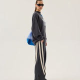 Person wearing a dark gray oversized sweatshirt and striped pants on a white background