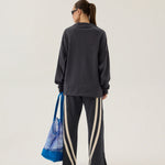 Person wearing a dark gray sweatshirt and pants with a blue bag on a white background