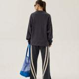 Person wearing a dark gray sweatshirt and pants with a blue bag on a white background
