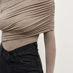 Beige long-sleeve top worn by a person on a plain background