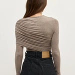 Person wearing a brown long-sleeve top and black pants on a white background