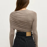 Person wearing a brown long-sleeve top and black pants on a white background