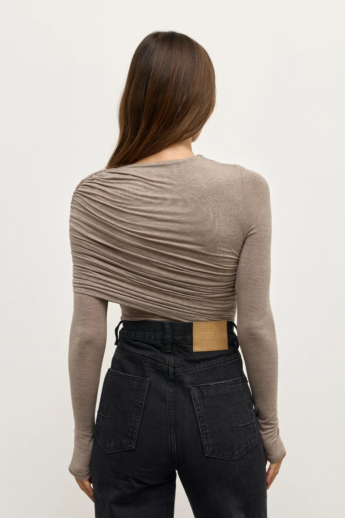 Person wearing a brown long-sleeve top and black pants on a white background