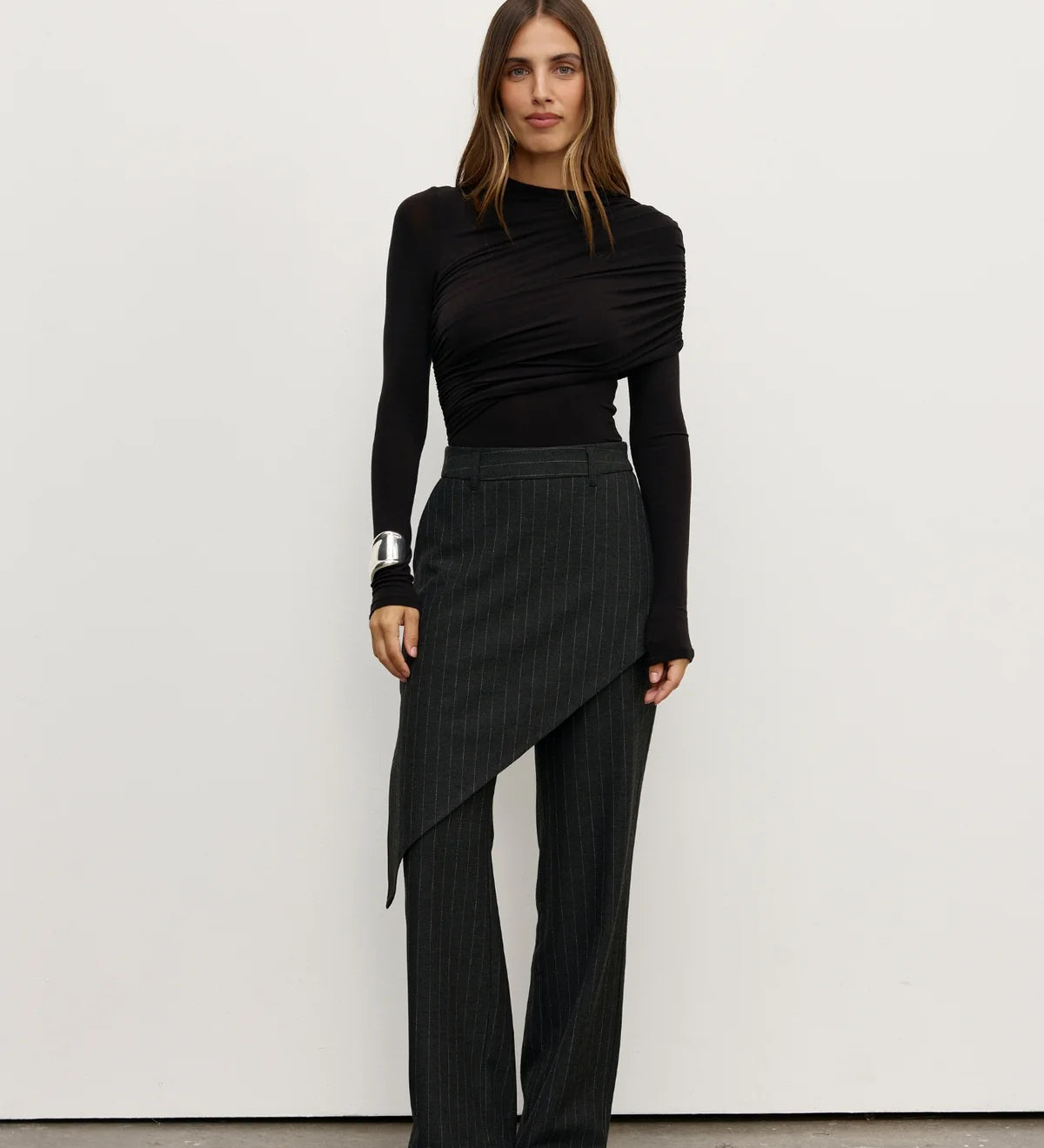Woman wearing a black outfit with a skirt and long sleeves against a white background