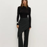 Woman wearing a black outfit with a skirt and long sleeves against a white background