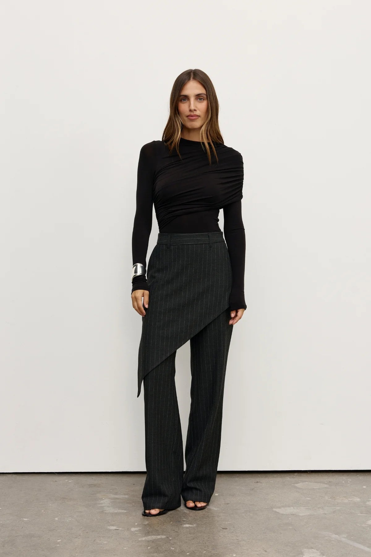 Woman wearing a black outfit with a skirt and long sleeves against a white background