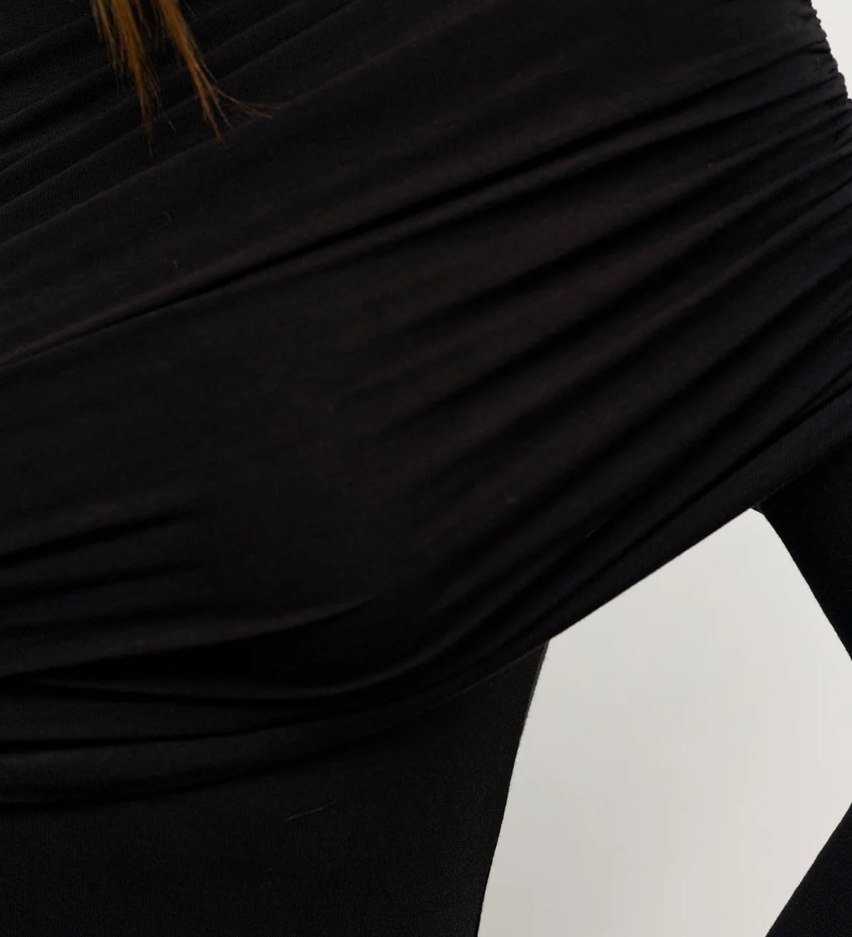 Close-up of a person wearing a black long-sleeve top with a white background