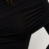 Close-up of a person wearing a black long-sleeve top with a white background