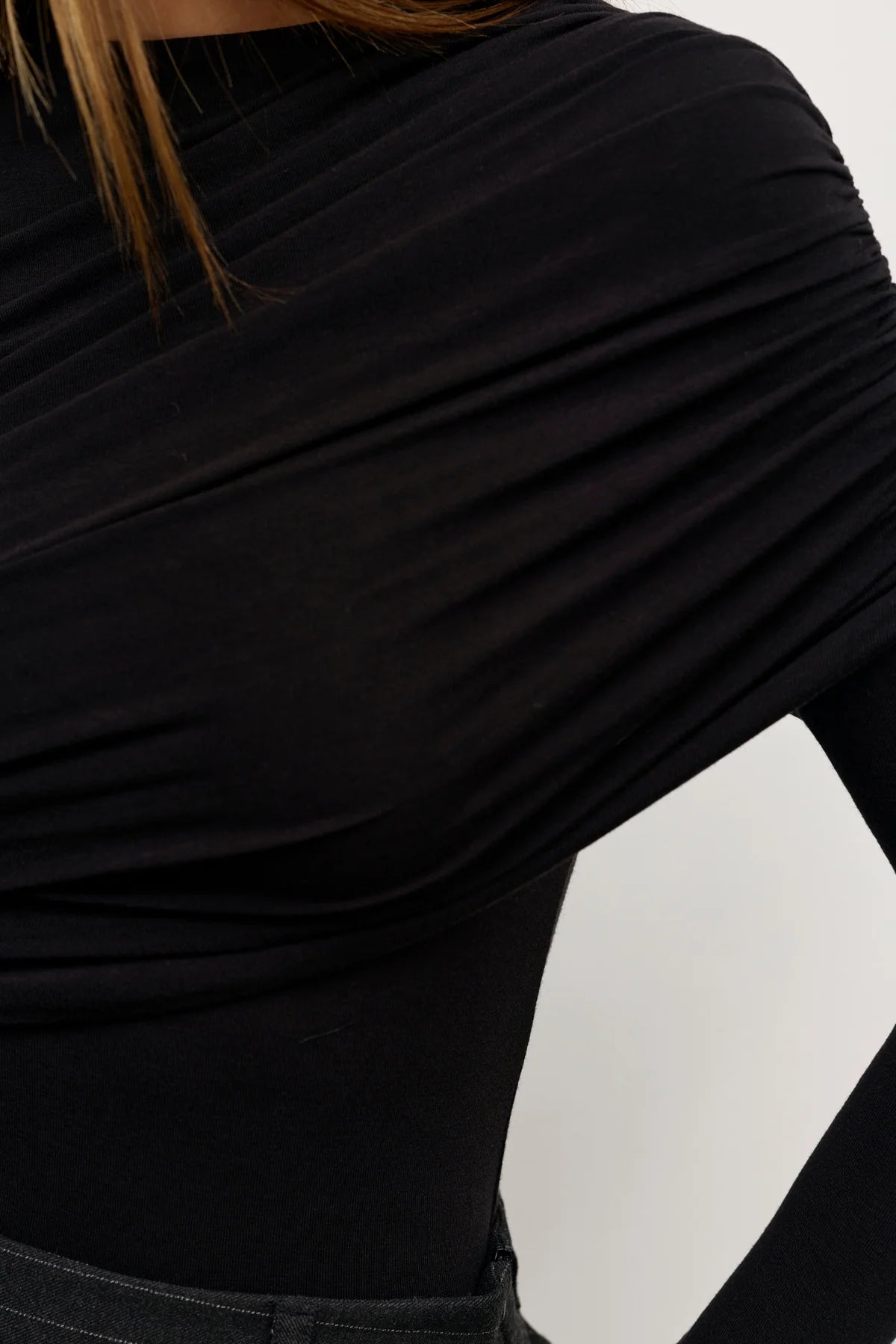 Close-up of a person wearing a black long-sleeve top with a white background