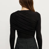 Woman wearing a black long-sleeve top and dark pants on a white background