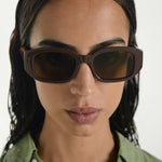 Woman wearing brown sunglasses with a plain background