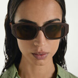 Woman wearing brown sunglasses with a plain background