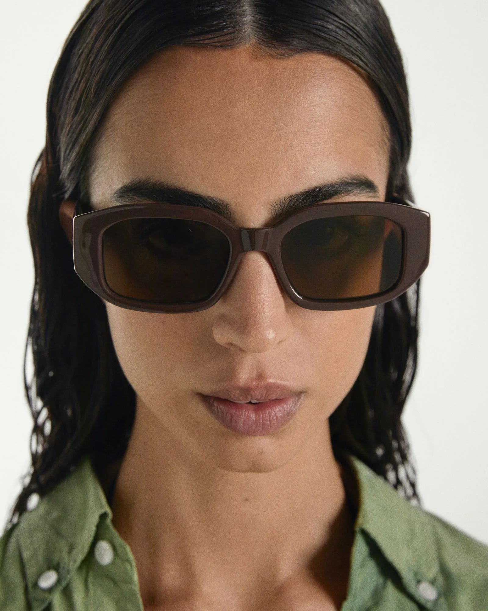 Woman wearing brown sunglasses with a plain background