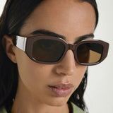 Person wearing a pair of sunglasses with a neutral background
