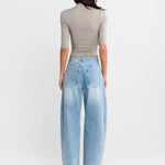 A woman shown from the back wearing a Steel grey half-sleeve ribbed  top and light-wash wide-leg denim jeans, paired with white heels, against a plain white studio background.