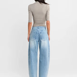 A woman shown from the back wearing a Steel grey half-sleeve ribbed  top and light-wash wide-leg denim jeans, paired with white heels, against a plain white studio background.
