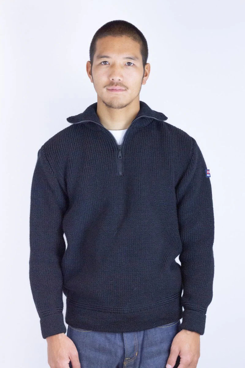 Man wearing a dark blue sweater with a small logo on a white background