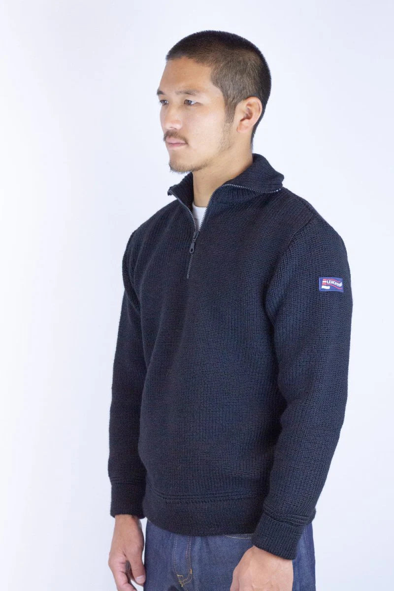 Man wearing a navy blue sweater with a logo on a white background
