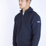 Man wearing a navy blue sweater with a logo on a white background