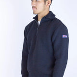 Man wearing a navy blue sweater with a logo on a white background