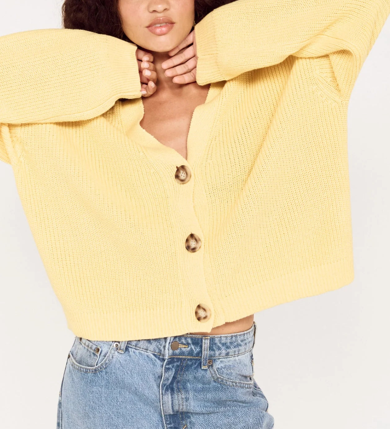 Person wearing a yellow sweater and light blue jeans on a white background