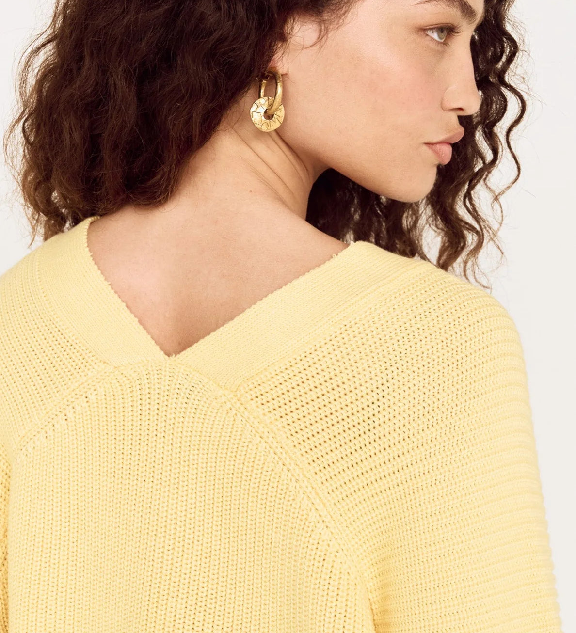 Woman wearing a yellow sweater against a white background