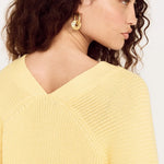 Woman wearing a yellow sweater against a white background