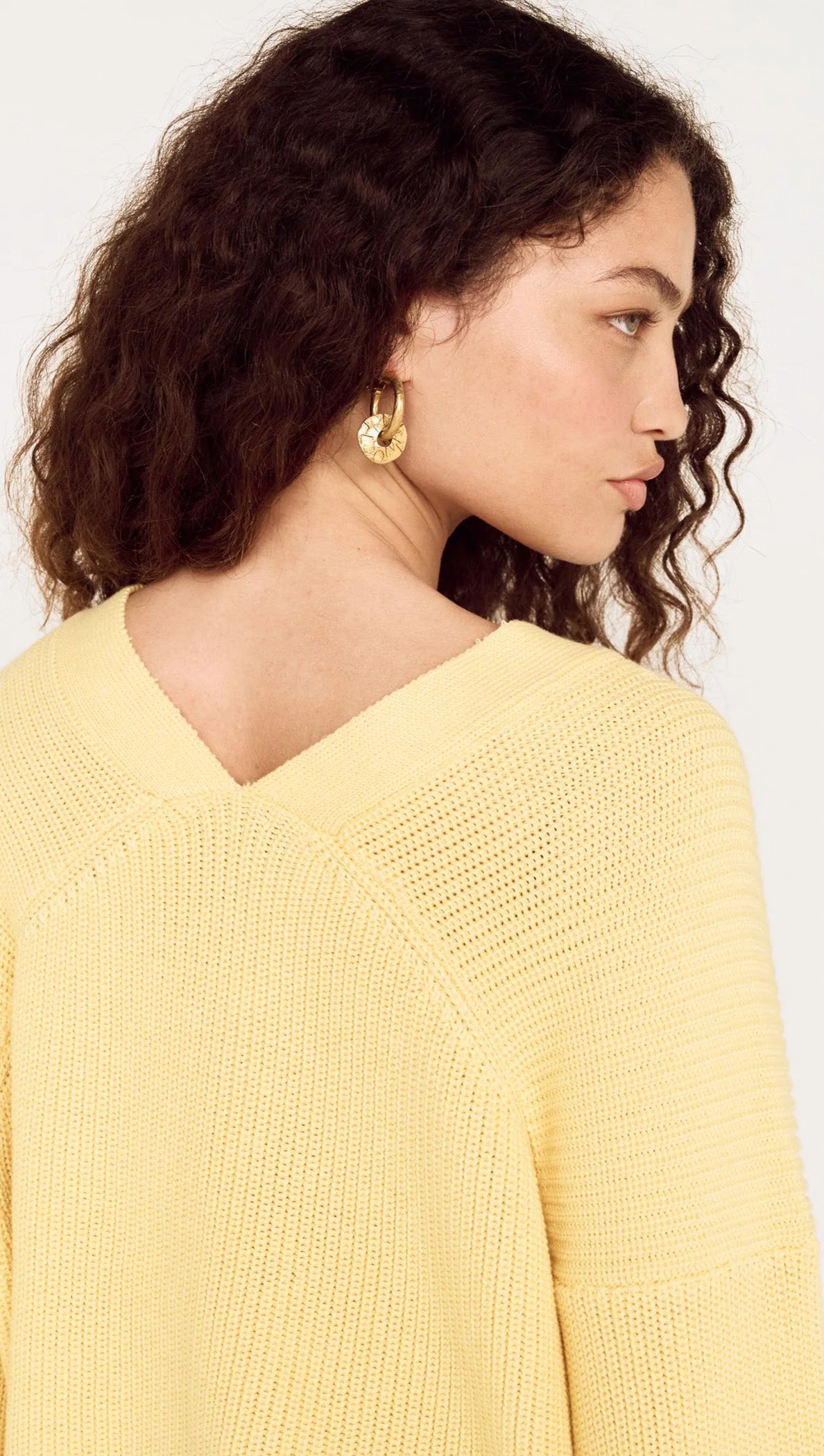 Woman wearing a yellow sweater against a white background