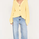 Person wearing a yellow sweater and light blue jeans on a white background