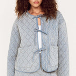 Woman wearing a light blue quilted jacket and skirt set on a white background