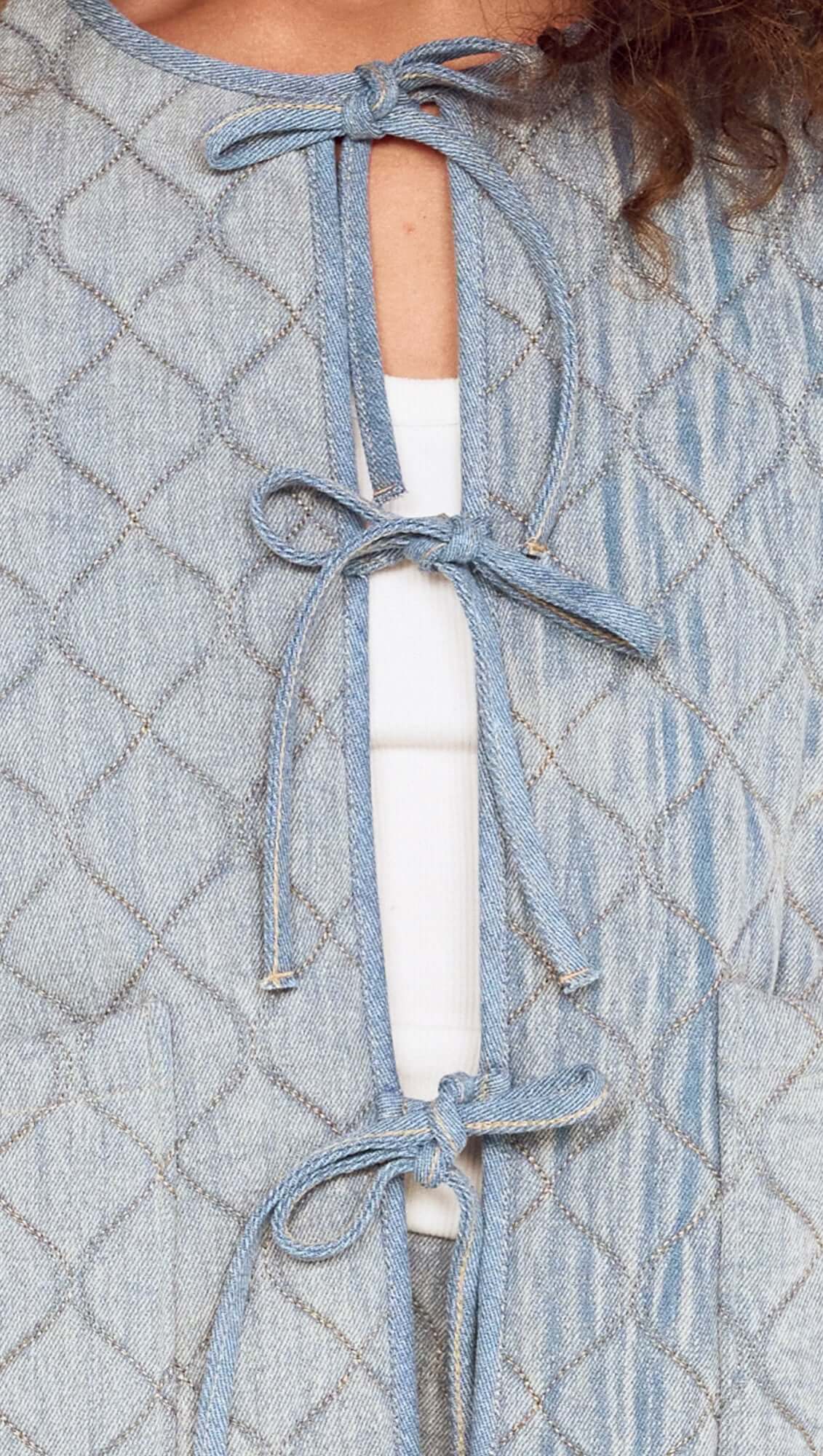 Light blue quilted jacket with tied front design over a white top.