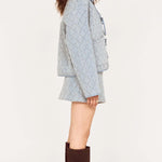 Woman wearing a light blue quilted jacket and brown knee-high boots on a white background