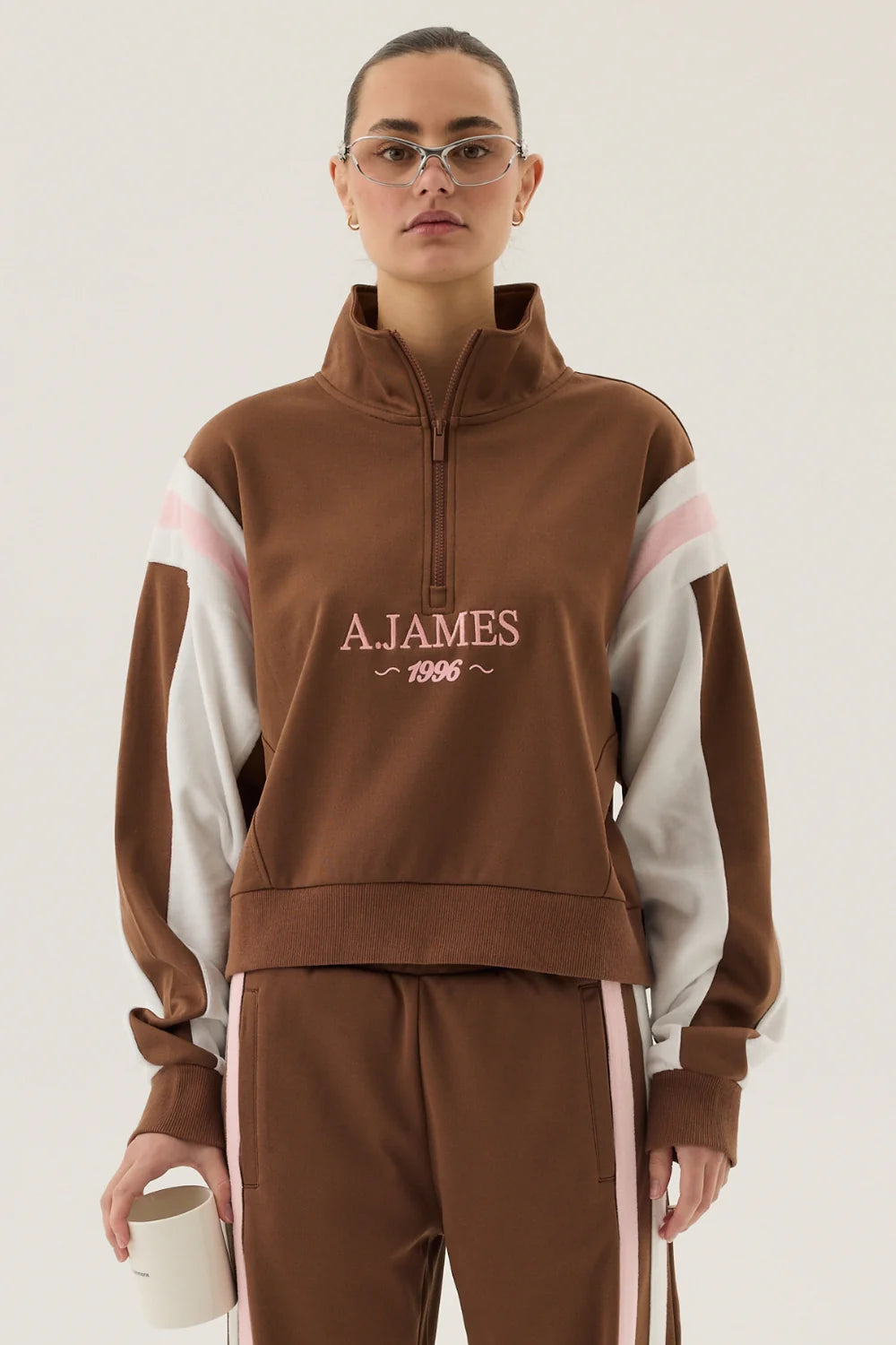 Person wearing a brown tracksuit with 'A.James' branding on a white background