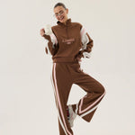 Person wearing a brown tracksuit with white stripes on a white background