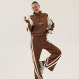Person wearing a brown tracksuit with white stripes on a white background