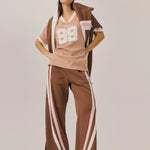 Person wearing a brown and white outfit with a cap on a plain background