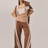 Person wearing a brown and white outfit with a cap on a plain background