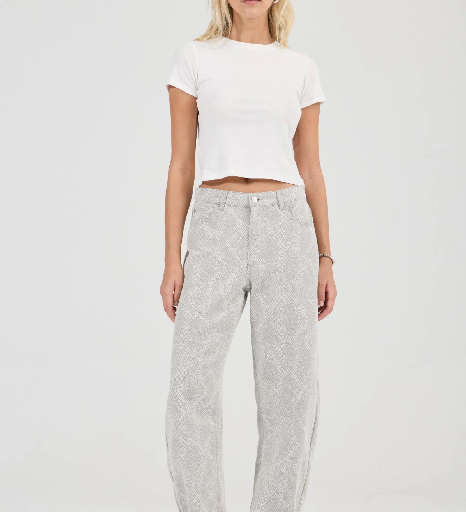 Woman wearing a white crop top and gray pants on a white background