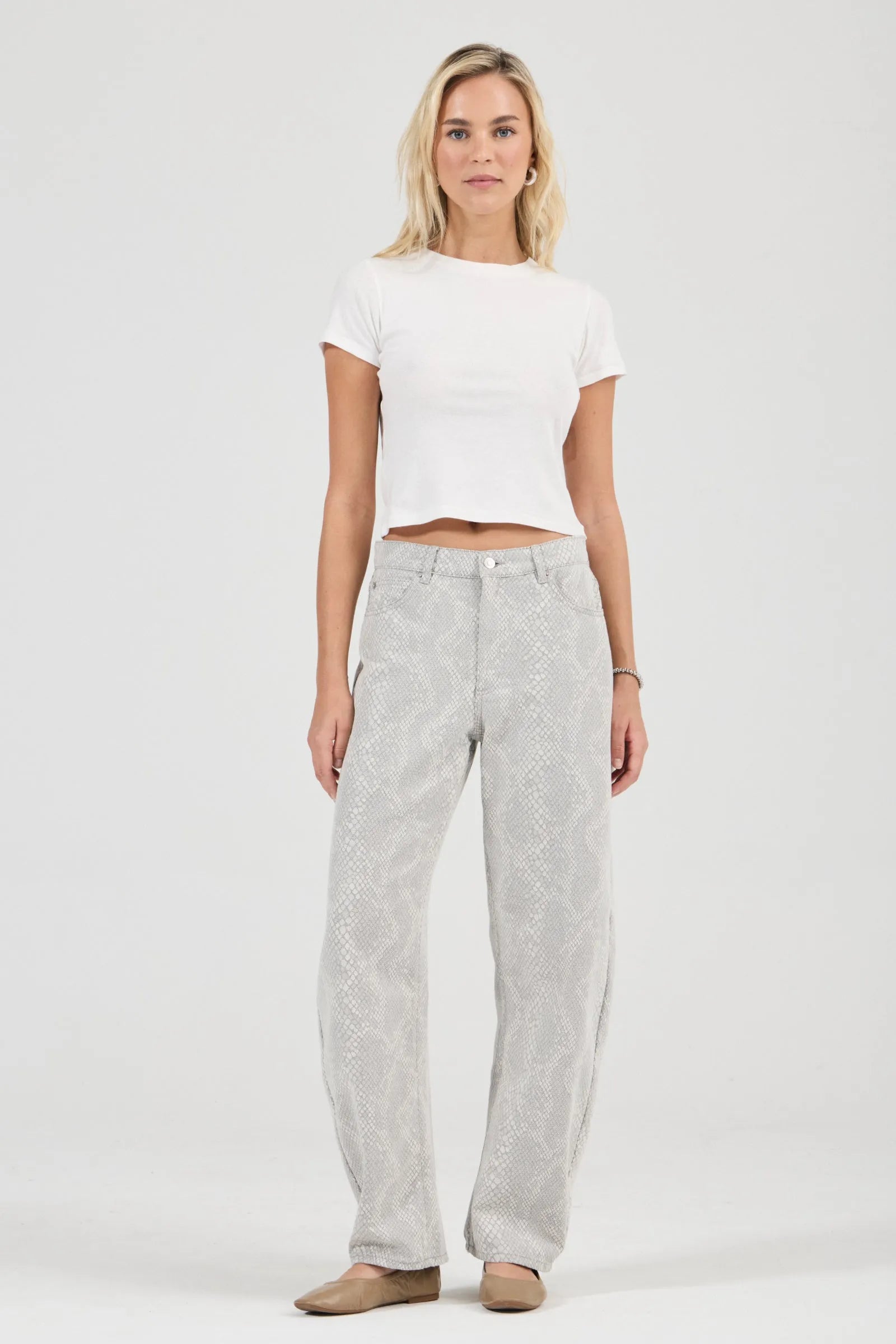 Woman wearing a white crop top and gray pants on a white background